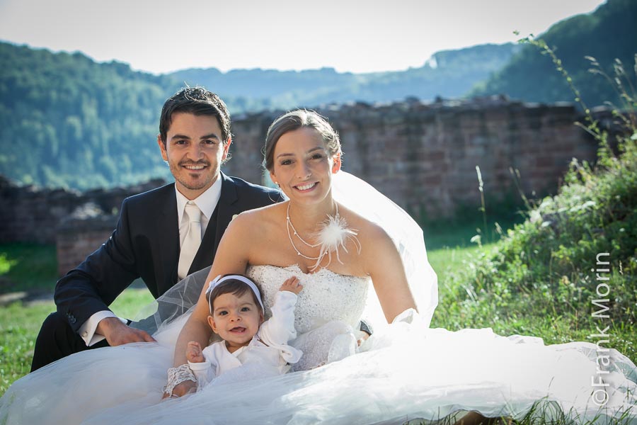 portrait des mariés assis dans l'herbe avec leur bébé