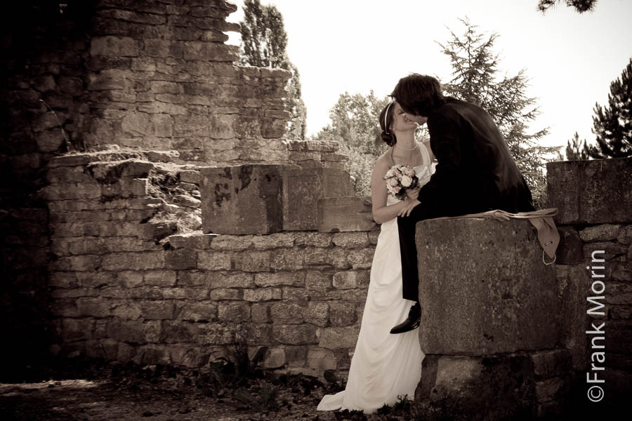 Les mariés s'embrassent, en Noir et blanc, avec le mari flou à l'arrière-plan