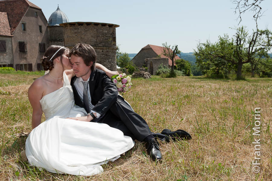 Les mariés assis dans l'herbe, le château en arrière-plan