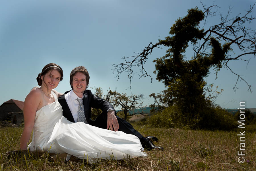 Les mariés assis dans l'herbe, un arbre couvert de lierre en arrière-plan