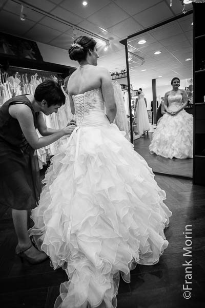 La Mariée se fait aider pour passer la robe devant un miroir