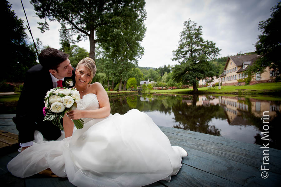 Les mariés au bord d'un étang, l'homme dépose un baiser sur la joue de sa fiancée