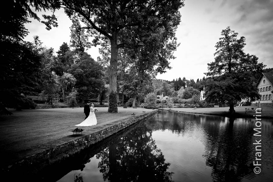 En Noir et Blanc, les mariés marchent au bord d'un étang