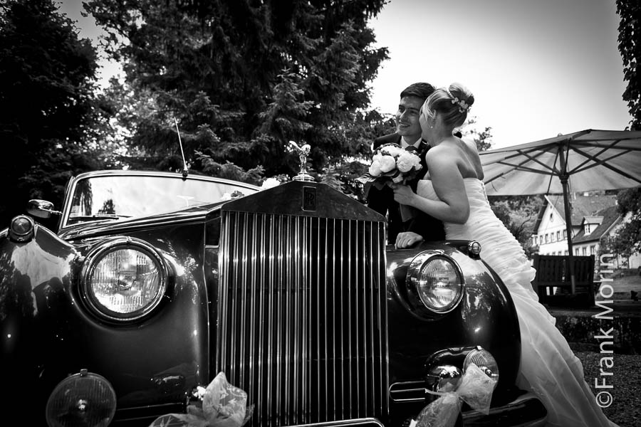 En Noir et Blanc, les mariés avec la callendre de leur Rolls Royce au premier plan