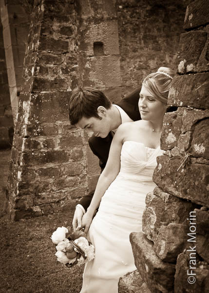 En noir et blanc dans un décor de batiment en ruine, les mariés regardent le bouquet
