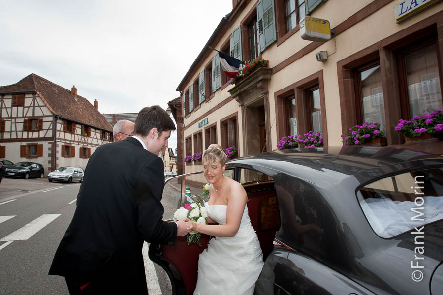 Le Marié aide sa fiancée à descendre de la voiture devant la mairie