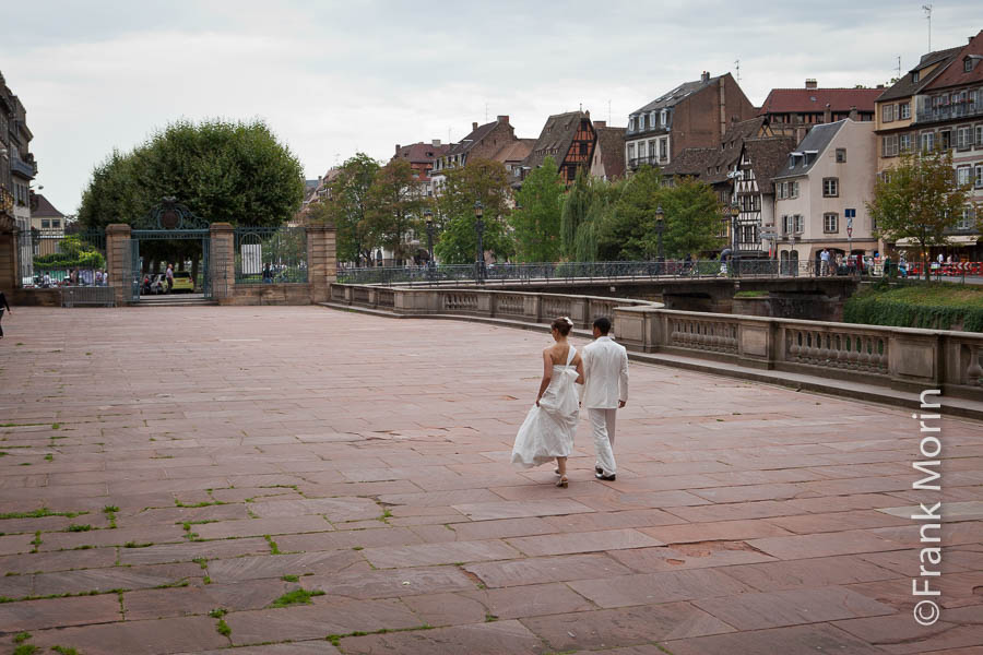 De dos, les mariés marchent sur une place pavée