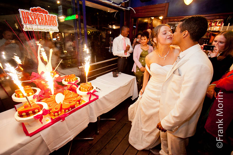 À l'intérieur de la péniche-restaurant les Mariés s'embrassent devant la pièce montée décorée de bougies à étincelles