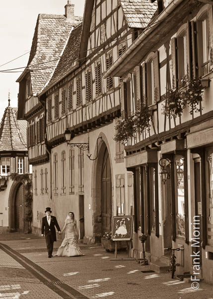 Les  Mariés marchent dans la rue d'un village alsacien, en Noir et Blanc sépia