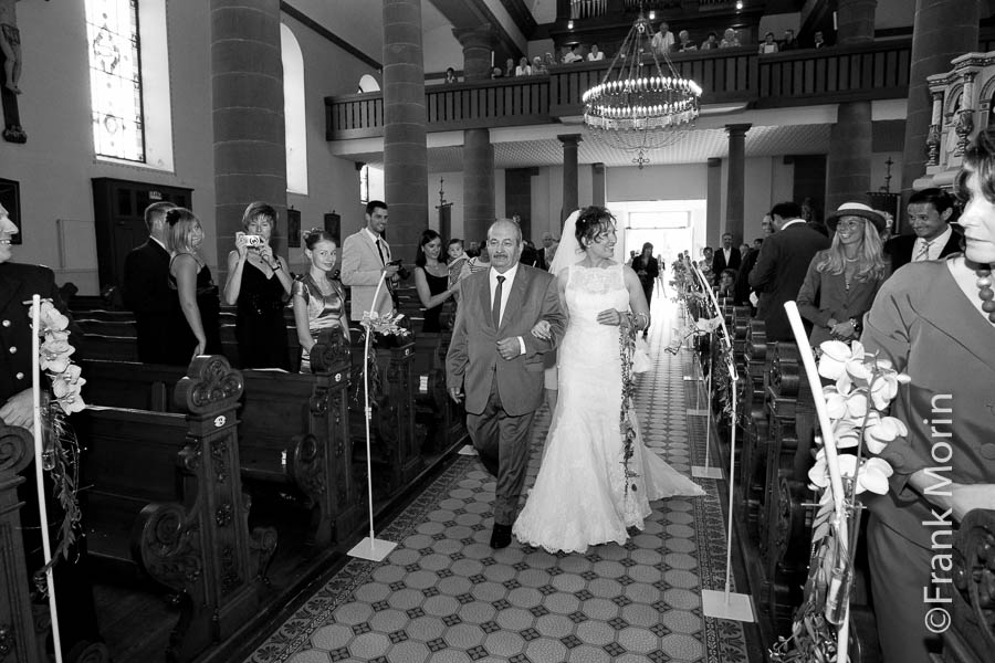 La Mariée au bras de son père dans l'allée centrale de l'église.