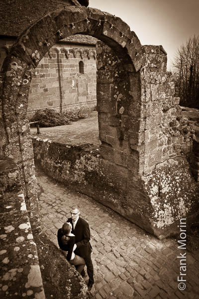 Les fiancés en tenue de ville à l'entrée d'un ancien château fort.