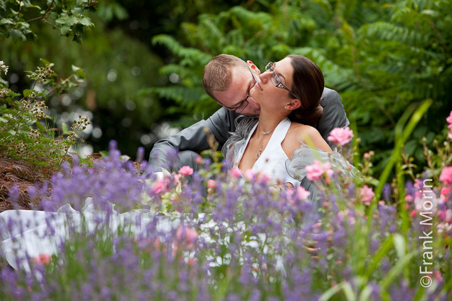 Les fiancés calinent assis au milieu des fleurs.