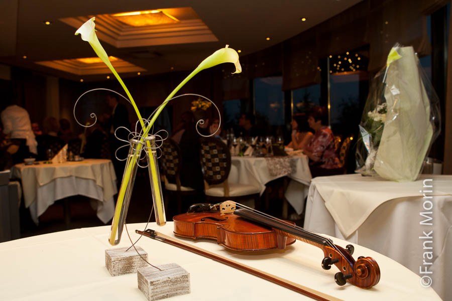 Un violon posé sur une table du restaurant avec l'archet et deux fleurs d'arum